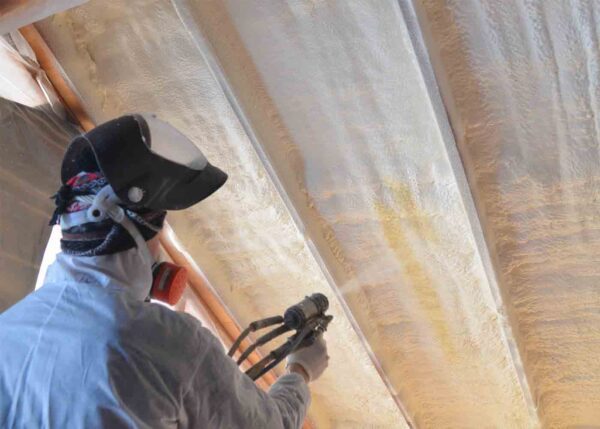 Photo of a worker spraying fireproofing foam on the underside of a roof