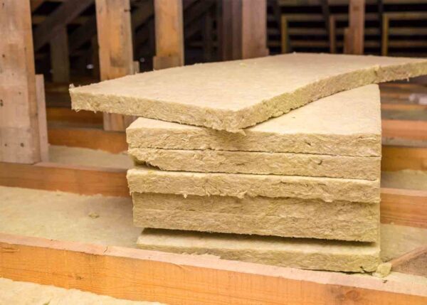 Image depicts beige insulation boards, which contained asbestos for many decades, in an attic construction area