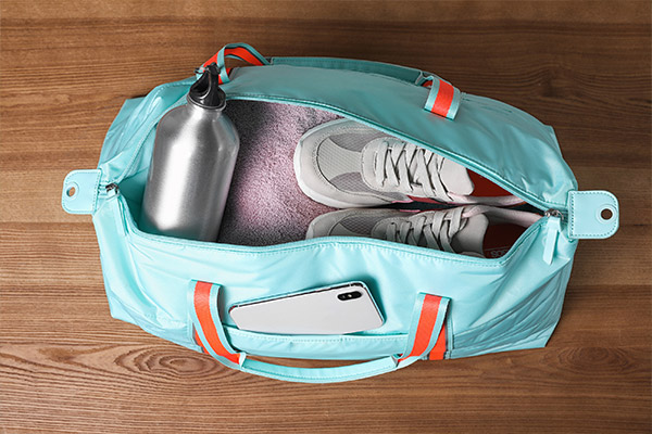 Open blue duffle bag showing water bottle, blanket and comfortable shoes, which may be included in a chemotherapy bag.