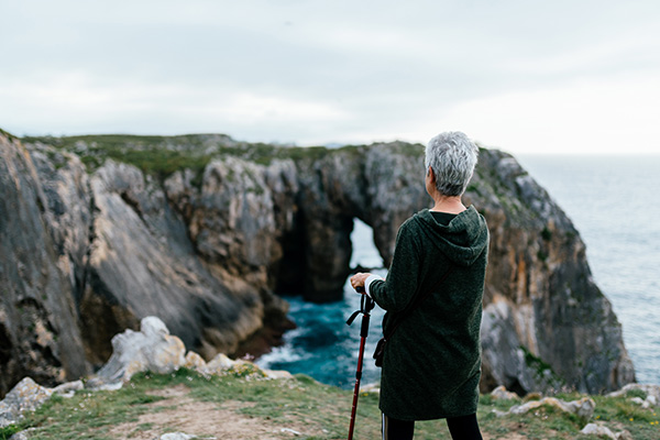 A mesothelioma patient with cropped, salt and pepper hair walks along a seaside cliff.