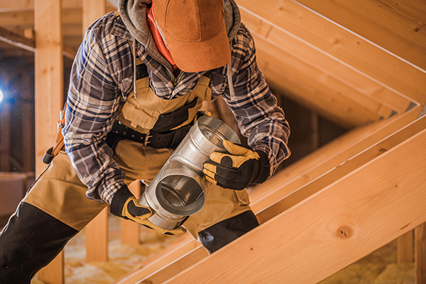 Photo of an HVAC worker handling air ducts. Connectors once used asbestos.