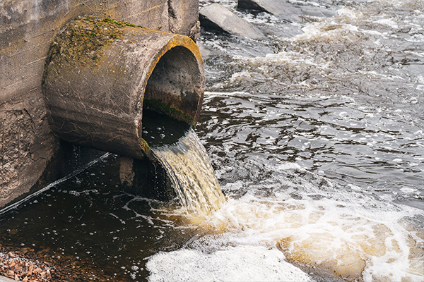 Dirty, contaminated water leaks out of a pipe into a water source.