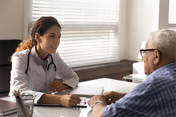 A doctor and patient sit across from each other, talking.