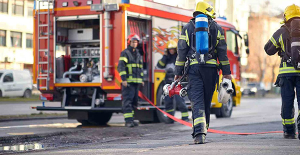 Firefighters standing near and running toward a fire truck