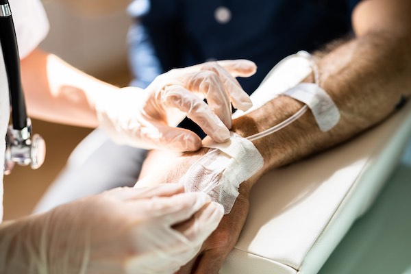 A nurse secures tubing to a patient's arm during an immunotherapy trial for peritoneal mesothelioma.